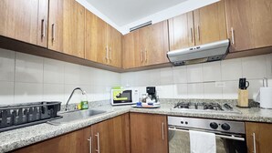 A kitchen with wooden cabinets, a stainless steel stove, a microwave, and a sink.