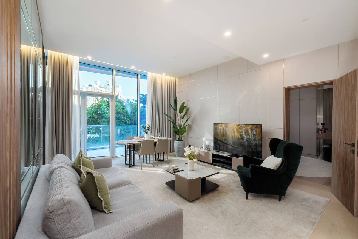 A modern living room with a sofa, coffee table, TV, and a dining area with a table and chairs.