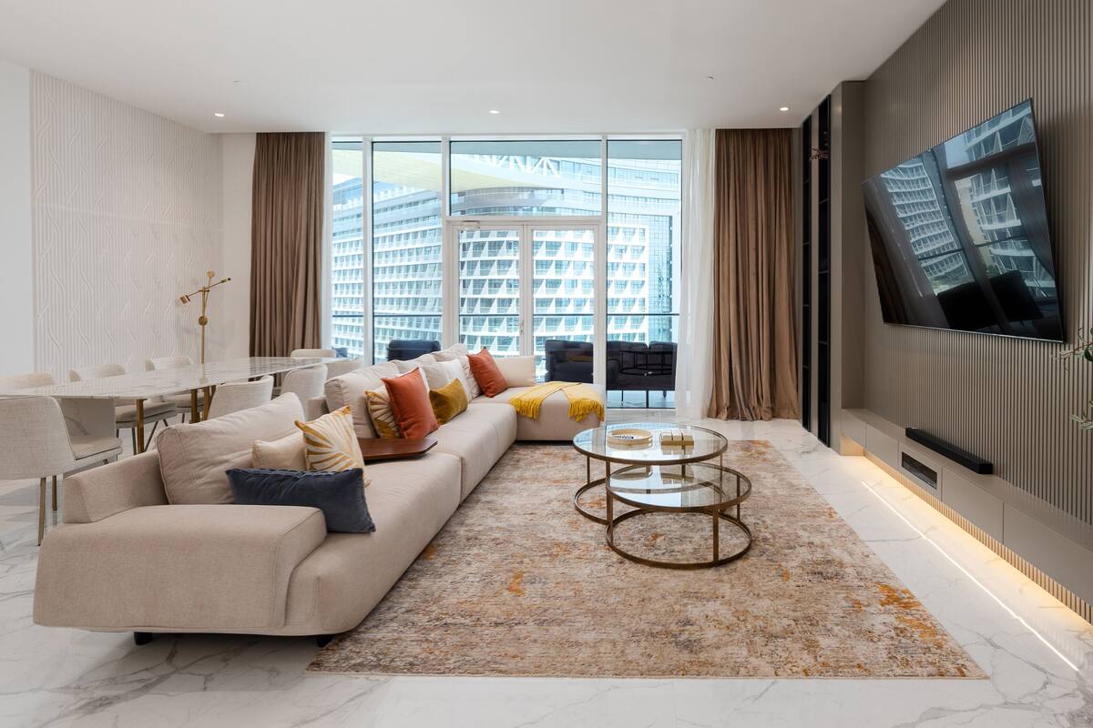 A modern living room with a sofa, coffee table, and a TV mounted on the wall.