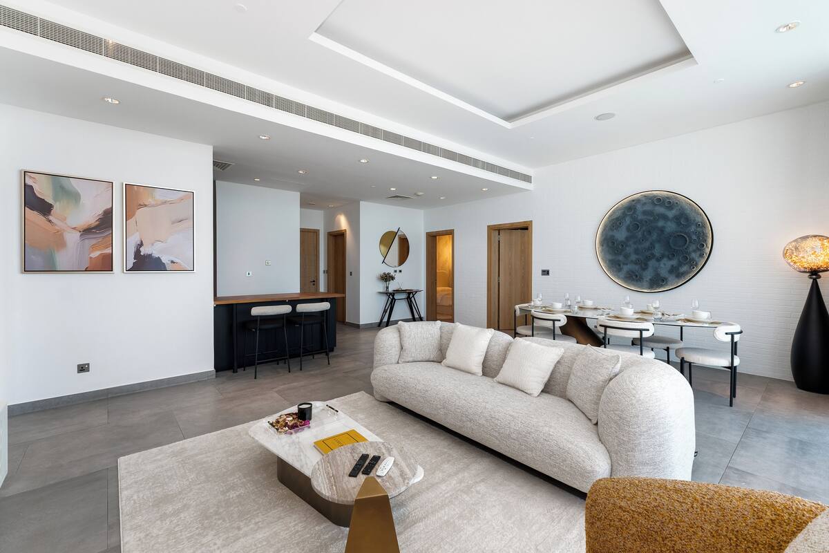 A modern living room with a sofa, coffee table, and dining area.
