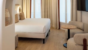 A modern hotel room with a large bed, a round table, and a TV. - Madame Drouot & Spa - Opéra (Paris)