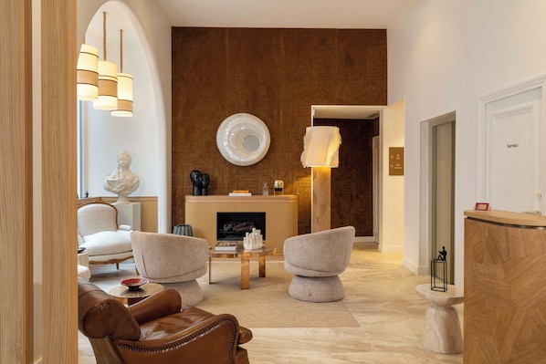 A modern living room with a fireplace, leather sofa, and contemporary furniture. - Madame Drouot & Spa - Opéra (Paris)