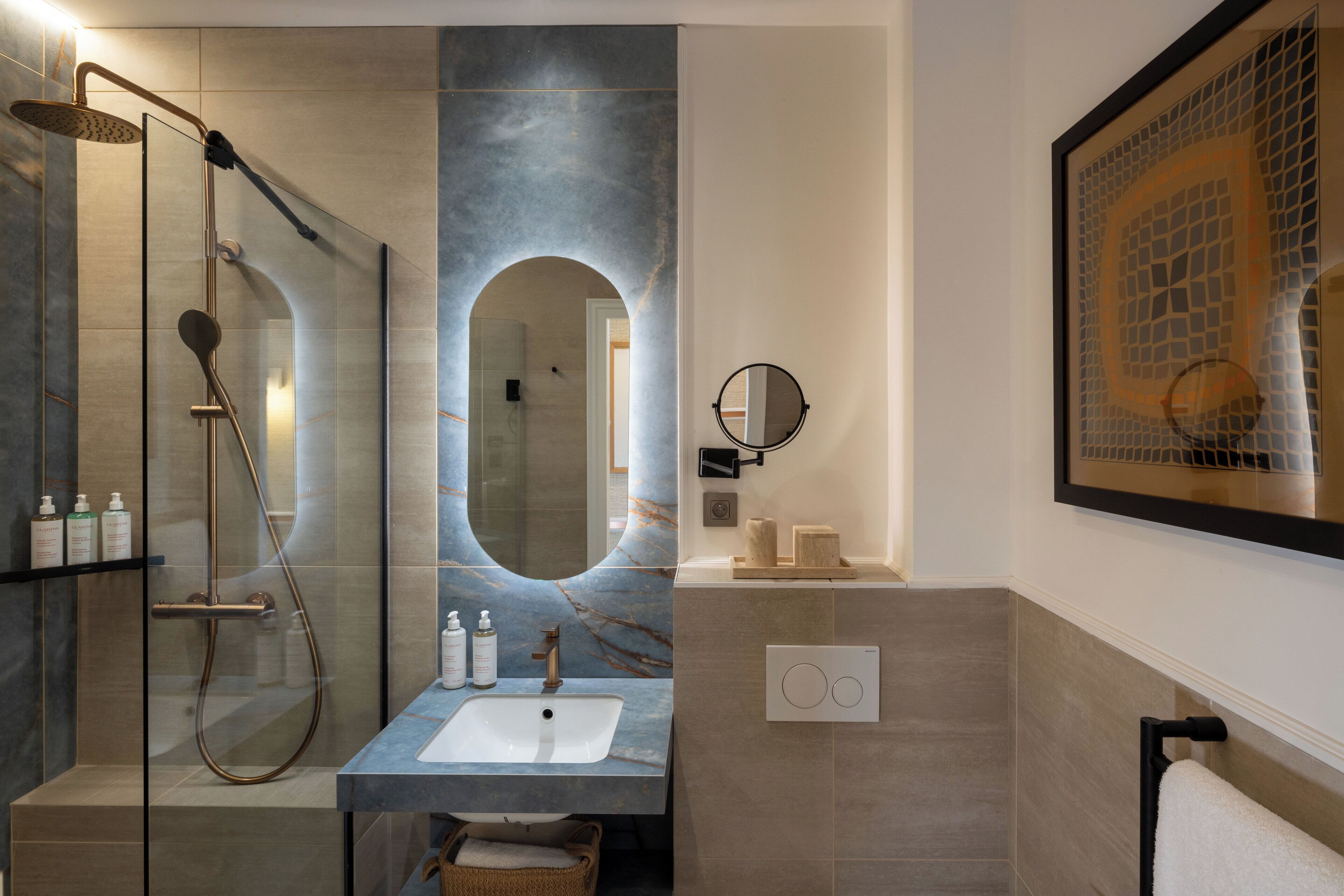 A modern bathroom with a glass-enclosed shower, a marble sink, and a large mirror.