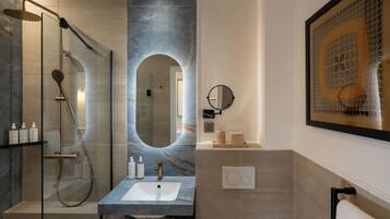 A modern bathroom with a glass-enclosed shower, a marble sink, and a large mirror.