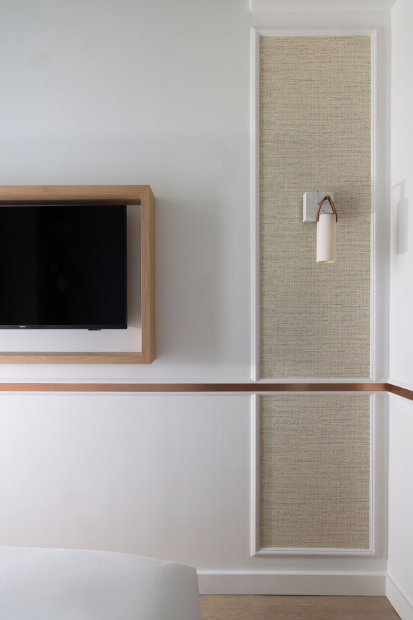 Habitación de hotel moderna con una televisión de pantalla plana montada en la pared, un panel de pared texturizado y una lámpara colgante.