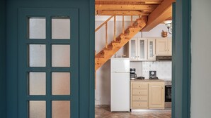 A kitchen with wooden stairs, a white refrigerator, and beige cabinets. - THALIA'S COTTAGE - Cozy, Romantic Retreat for Two (Samos)