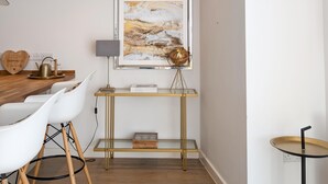 A modern kitchen with white chairs, a wooden table, a gold-framed globe, and a framed abstract painting on the wall. - Newquay Escape/10 min to Beach/patio/parking (Newquay)