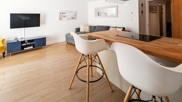 A modern kitchen with a wooden countertop, white chairs, and a built-in stove. - Newquay Escape/10 min to Beach/patio/parking (Newquay)