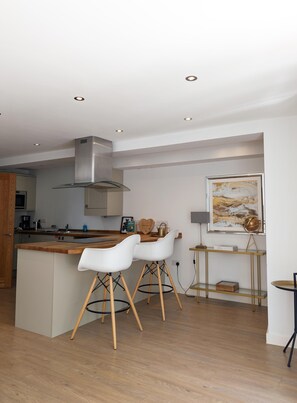 Une cuisine moderne avec un îlot central, des chaises blanches et un grand tableau accroché au mur.