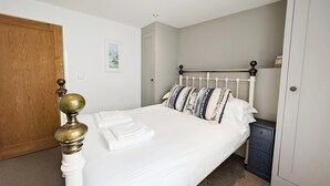 A bedroom with a bed, a nightstand, a wooden door, and a wall-mounted picture. - Newquay Escape/10 min to Beach/patio/parking (Newquay)