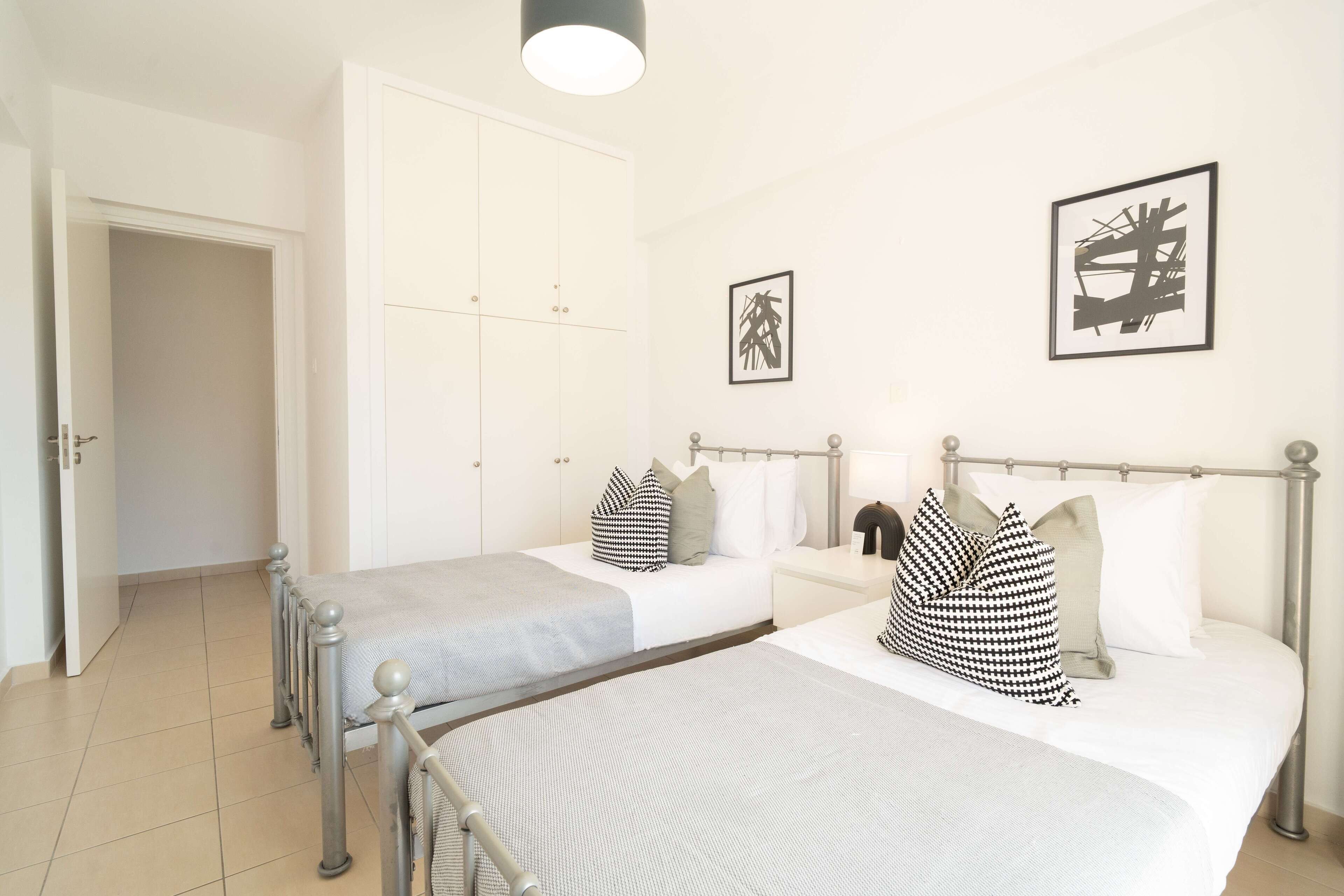 Quarto de hotel com duas camas, um guarda-roupa e obras de arte nas paredes.