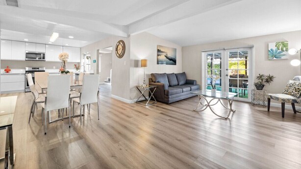 A spacious living area with a grey sofa, a dining table with chairs, and a kitchen in the background. - Tranquil Escape Pool Hot Tub Game Room (San Diego)