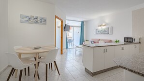 A modern kitchen with white cabinets, a granite countertop, and a dining area with a round table and white chairs.