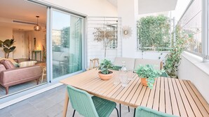 A modern living space with a wooden table, green chairs, a sofa, and potted plants. - Apartment 'Db01 Duna Beach Casa Zen' with Shared Pool, Wi-Fi and Air Conditioning (Torrox)