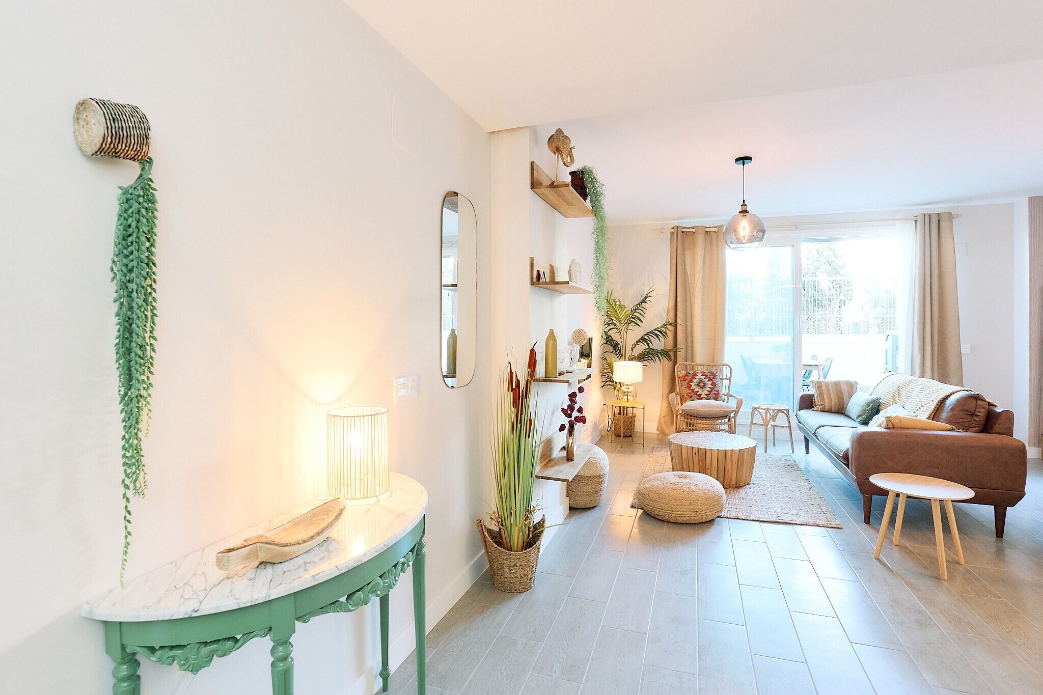 A living room with a sofa, a coffee table, a lamp, and a hanging plant.