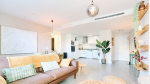 A modern living room with a sofa, ottomans, and a dining area with a table and chairs. - Apartment 'Db01 Duna Beach Casa Zen' with Shared Pool, Wi-Fi and Air Conditioning (Torrox)