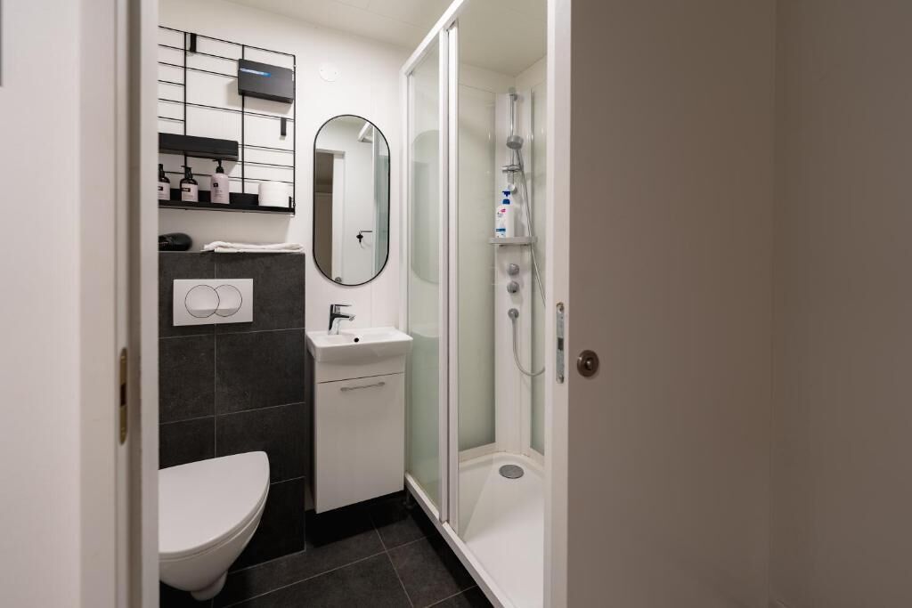 A modern bathroom with a toilet, sink, mirror, and glass-enclosed shower.