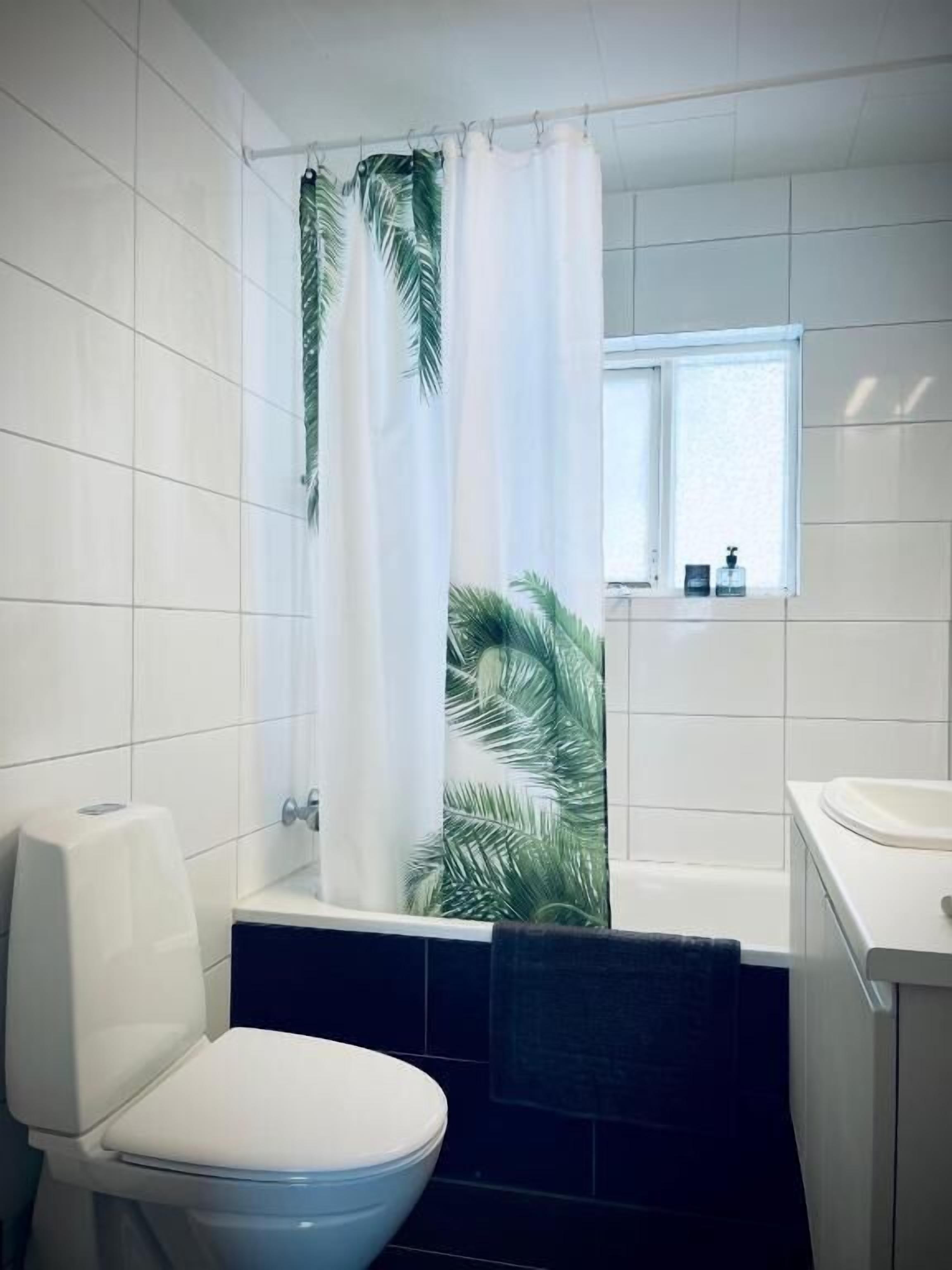 A bathroom with a toilet, bathtub, and a window above the sink.