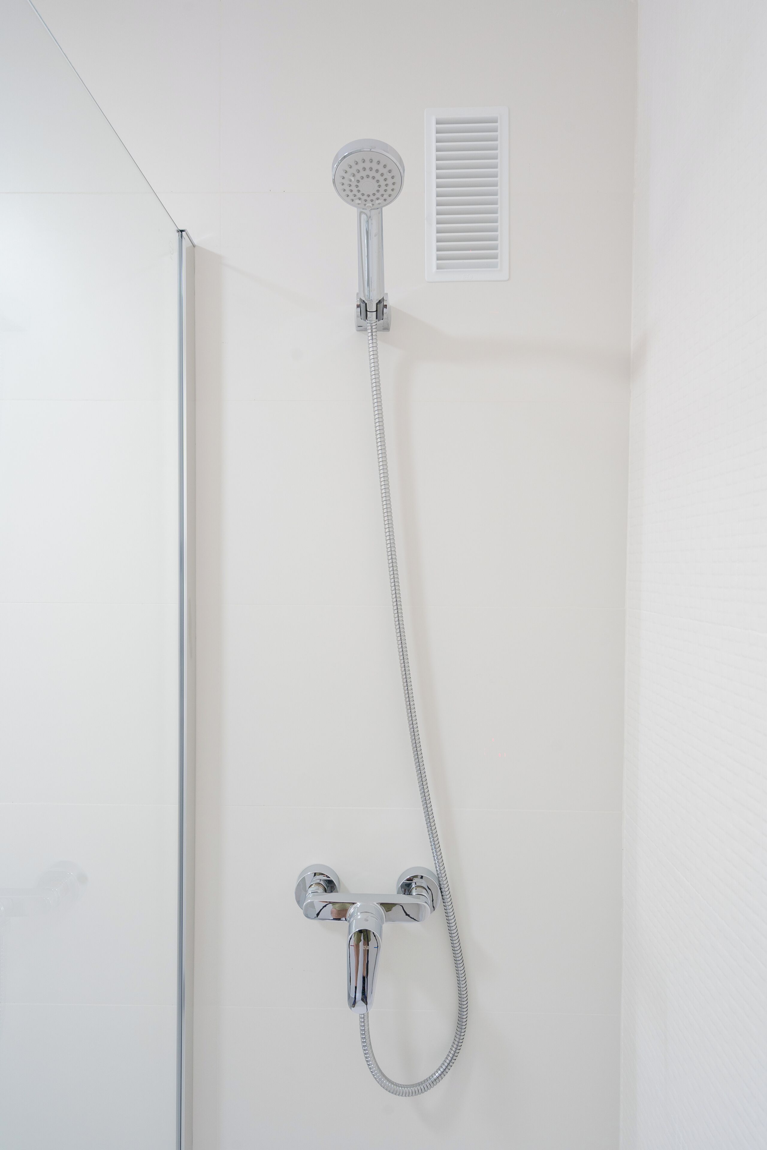 Ducha con cabezal de ducha de mano y grifo empotrado en la pared.