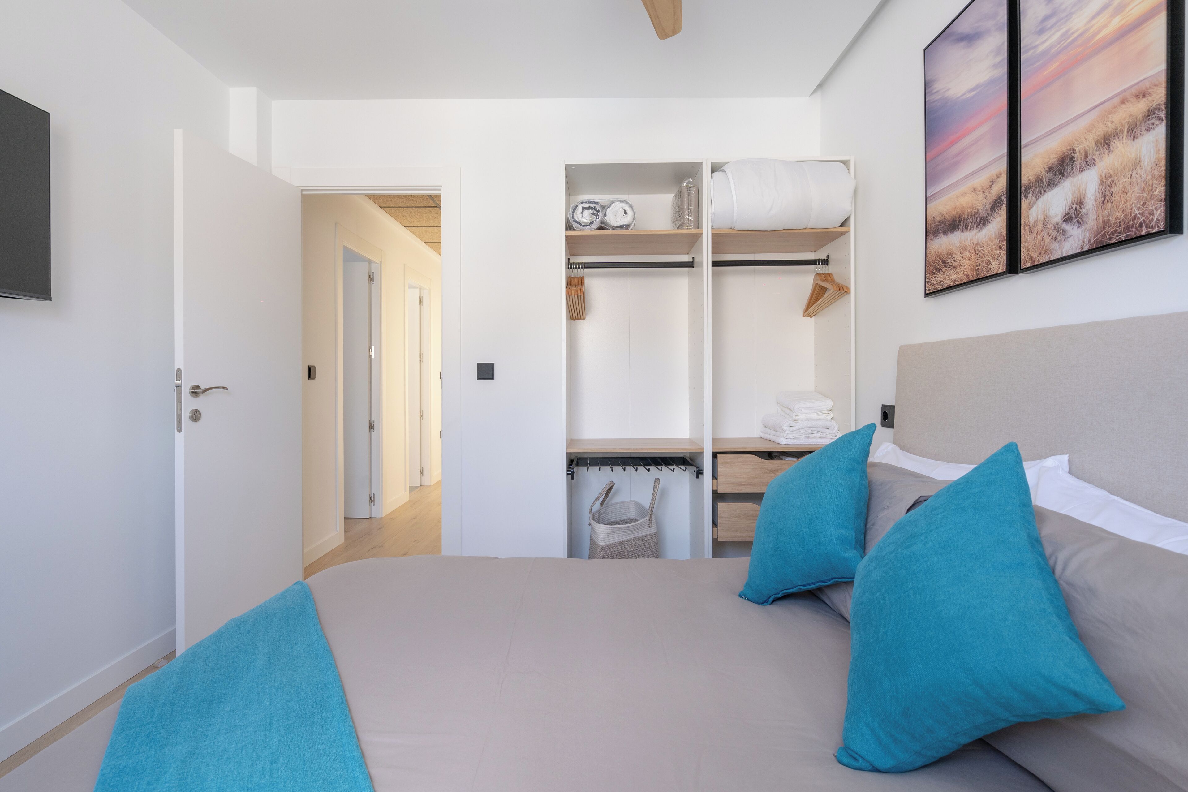 A bedroom with a bed, two pillows, a wardrobe, and a painting on the wall.
