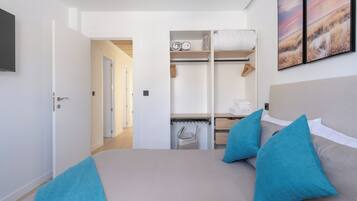 A bedroom with a bed, two pillows, a wardrobe, and a painting on the wall.