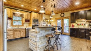 A kitchen with wooden cabinets, a stone island, bar stools, and pendant lighting.
