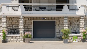 Un edificio de fachada de piedra, puerta de garaje y macetas.