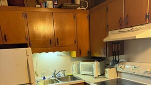 A kitchen with wooden cabinets, a white refrigerator, a microwave, a stove, and a sink. - Bellawood Resort #5 - Lake Cabin with boat slip (Greers Ferry)