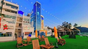 A hotel with outdoor seating, a pool, and a building with multiple floors and balconies.