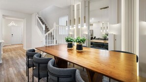 Un espace repas moderne avec une table en bois, des chaises à revêtement gris et des plantes en pot.