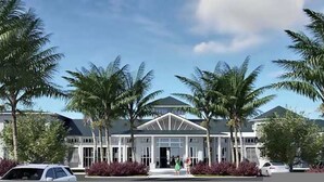 Un hôtel moderne à la façade symétrique, doté de grandes fenêtres et bordé de palmiers au premier plan.