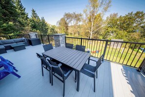 Een terras buiten met een houten tafel en stoelen, een ingebouwde bank en een stenen open haard.