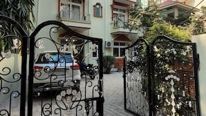 A gated entrance to a residential building with multiple balconies and a car parked inside.