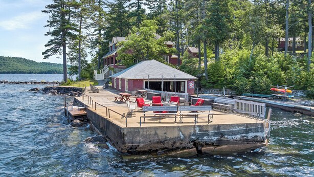 A docked house with a covered patio, outdoor seating, and a view of the water. - Lake Winnipesauke sleeps 9 with stunning sunset views (Alton Bay)