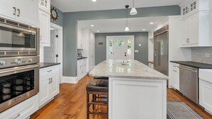 A modern kitchen with white cabinetry, stainless steel appliances, and a central island. - Lake Winnipesauke sleeps 9 with stunning sunset views (Alton Bay)