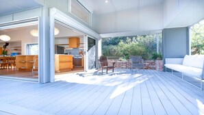 Un espacio de sala-comedor abierto con cocina, zona de comedor y terraza con mobiliario exterior.