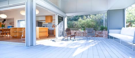 Een open woonoppervlak met keuken, eethoek en terras met tuinmeubilair.