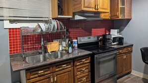 A kitchen with wooden cabinets, a stainless steel sink, a microwave, and a stove.
