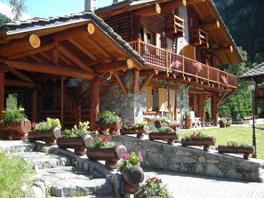 A wooden cabin with a balcony, stone foundation, and flower planters. - Chalet-village Situated in a Quiet Area (Antey-Saint-Andre)