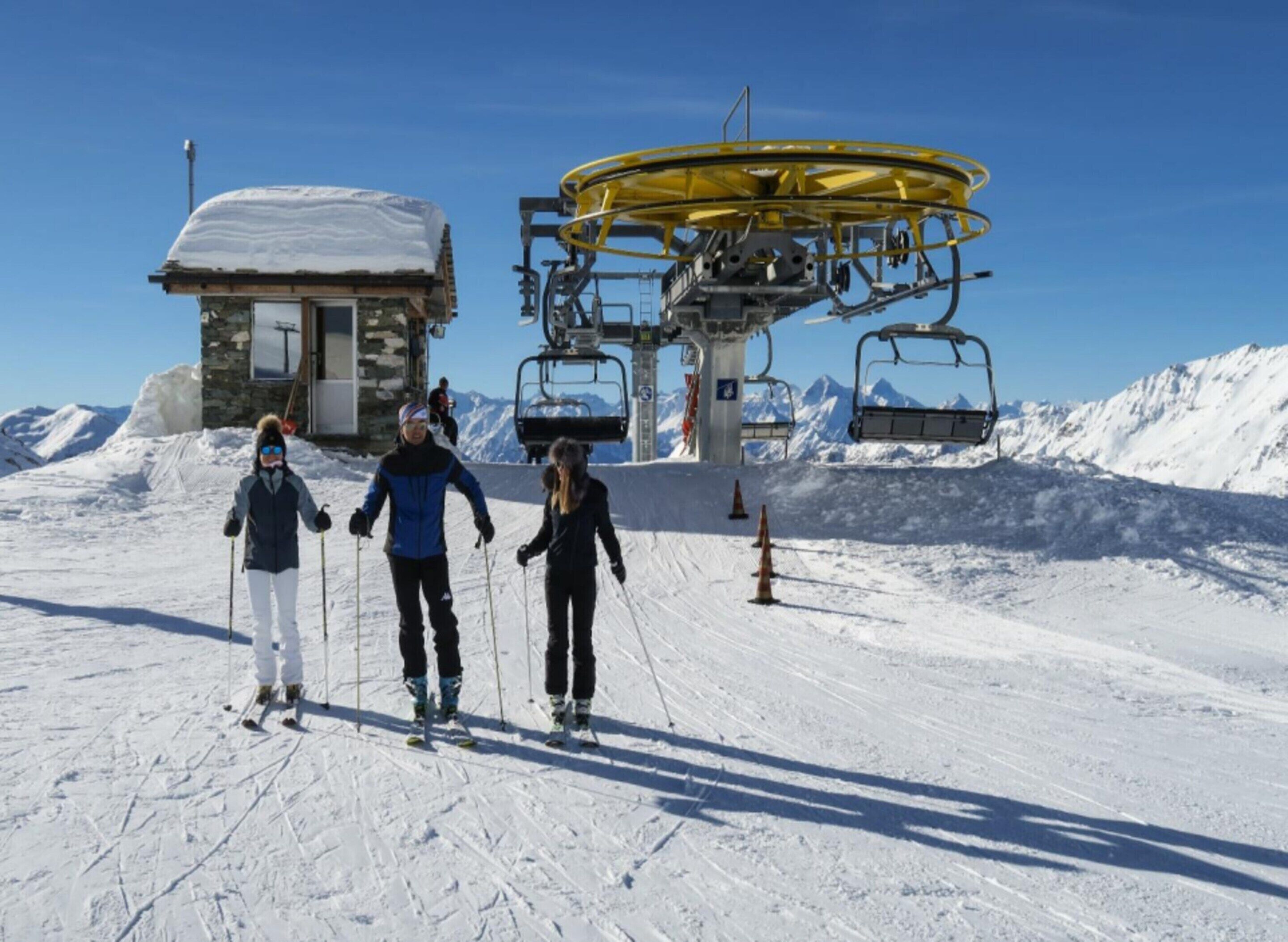 Un télésiège avec trois skieurs au premier plan.