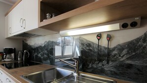 Una cocina moderna con un lavamanos de acero inoxidable, armarios de madera y un salpicadero con motivos de montaña.