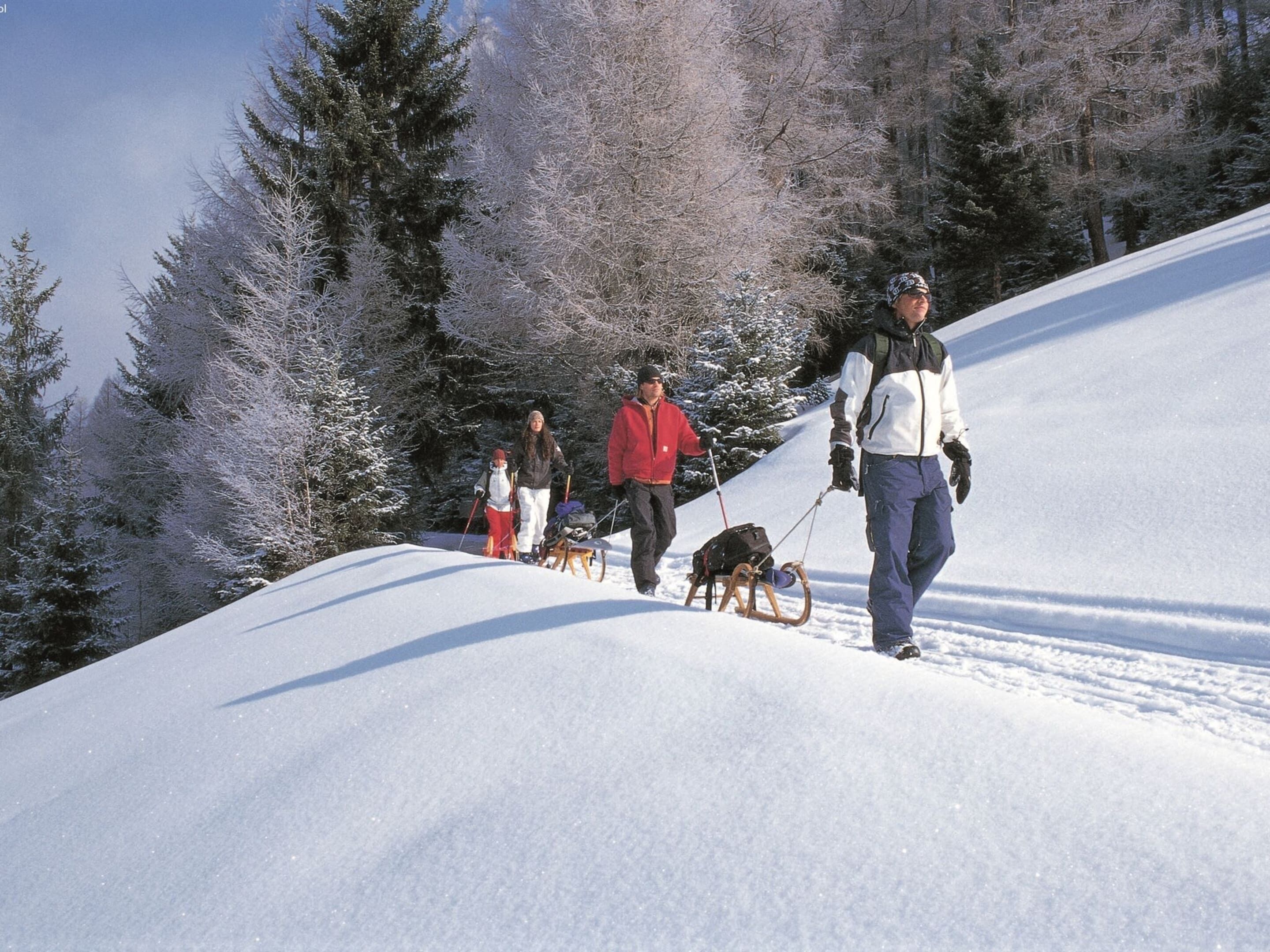 Paisaje nevado con personas esquiando y caminando.