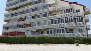 A multi-story building with balconies, a red roof, and a gravel ground. - Welcoming Apartment in Marotta at the Seabeach (Mondolfo)