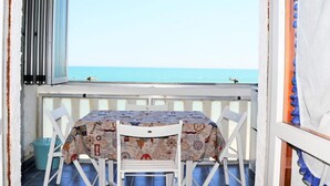 A balcony with a table and chairs, overlooking a clear blue sea. - Welcoming Apartment in Marotta at the Seabeach (Mondolfo)