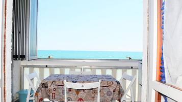 A balcony with a table and chairs, overlooking a clear blue sea.