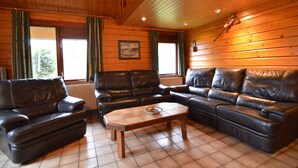 A cozy living room with two leather sofas, a wooden coffee table, and a fireplace. - Comfortable Chalet in Ovifat Near Ski Lift (Waimes)