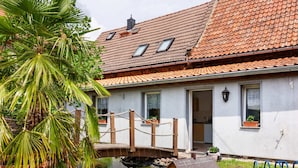 A house with a tiled roof, a small pond, and a wooden structure.