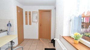 A small, bright room with a window, a radiator, a table, and a chair.