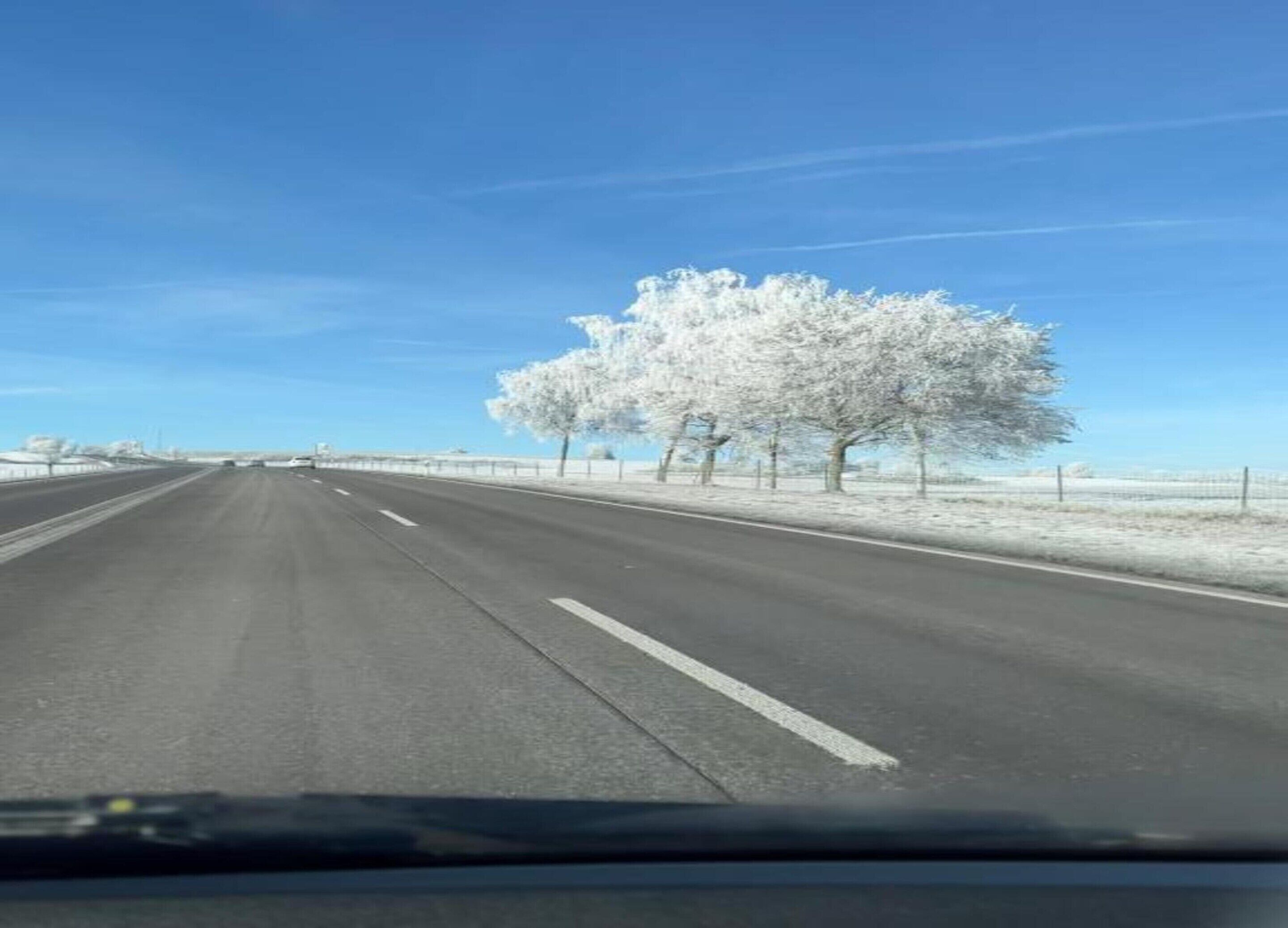 Eine Autobahn mit schneebedeckten Bäumen und einem klaren Himmel.