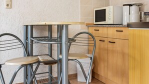 A compact kitchen with a metal table and chairs, a microwave, and wooden cabinets.